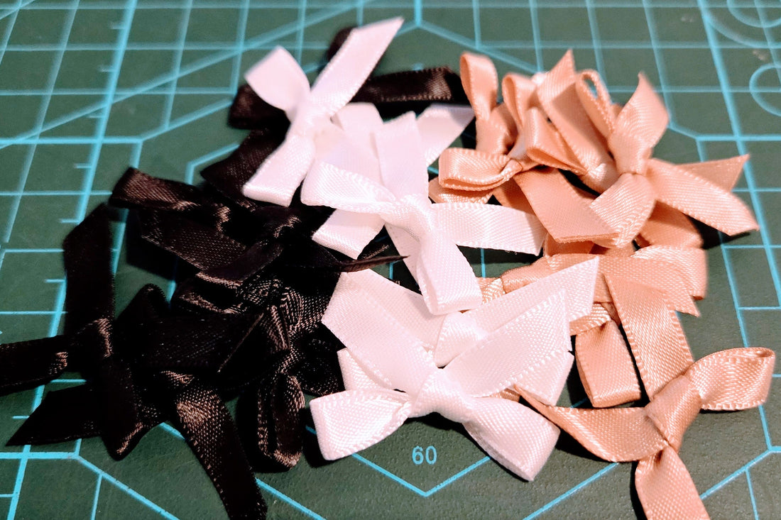 Assorted black, white, and pink hair bows on a green cutting mat.