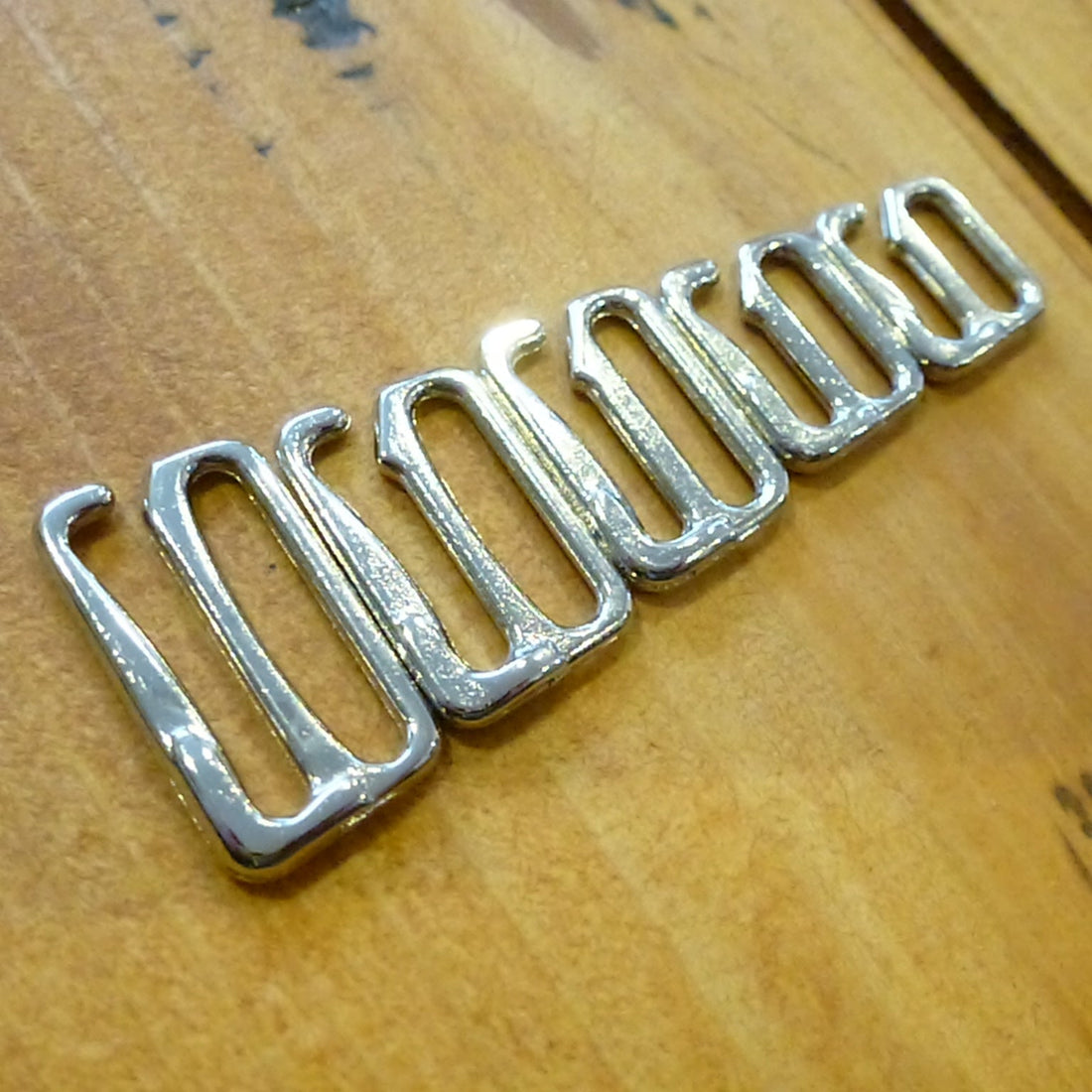 Nickel plated bra or swim hooks on a wood surface