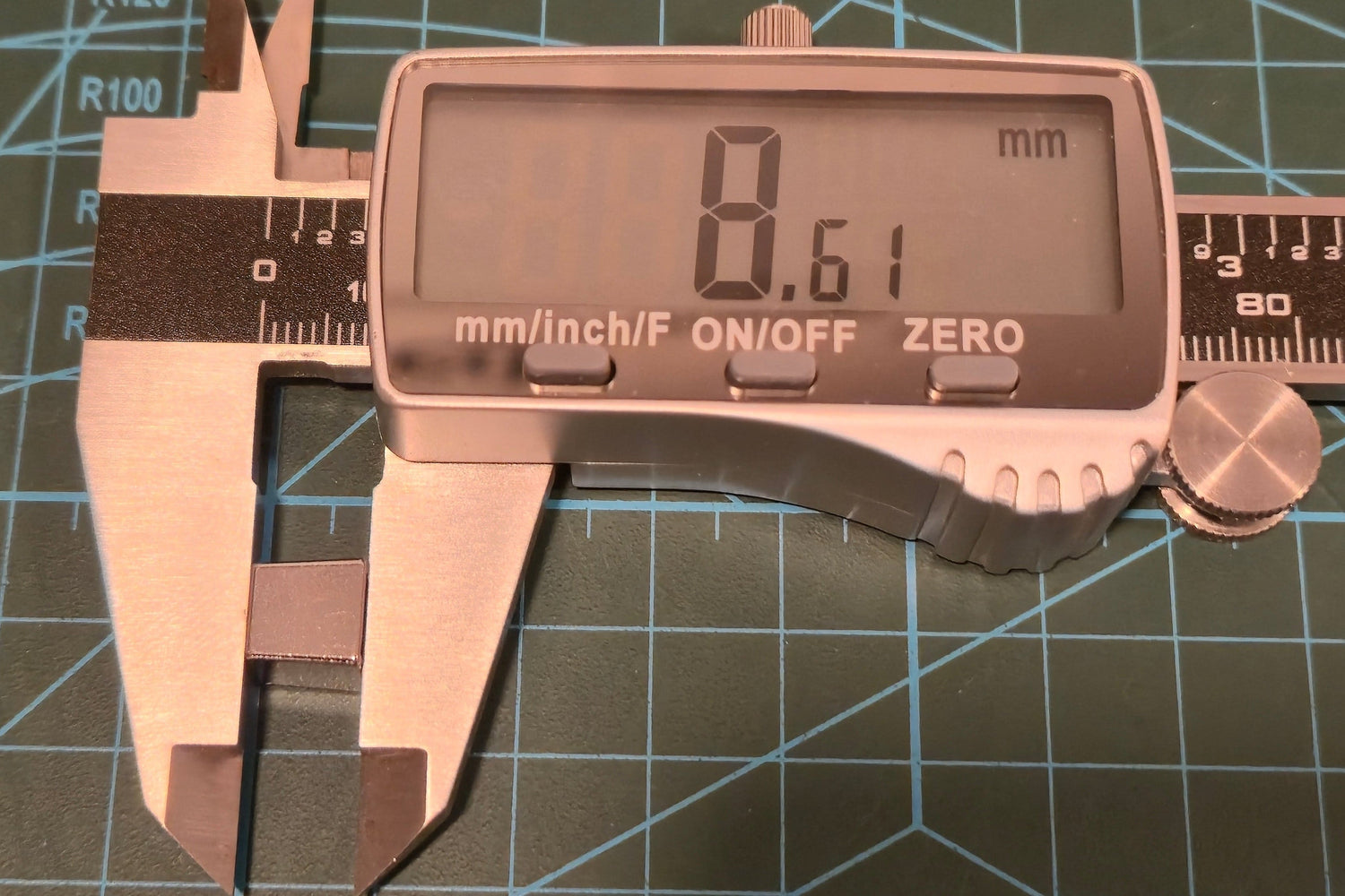 Digital caliper showing a measurement of 8.61 mm on a grid background